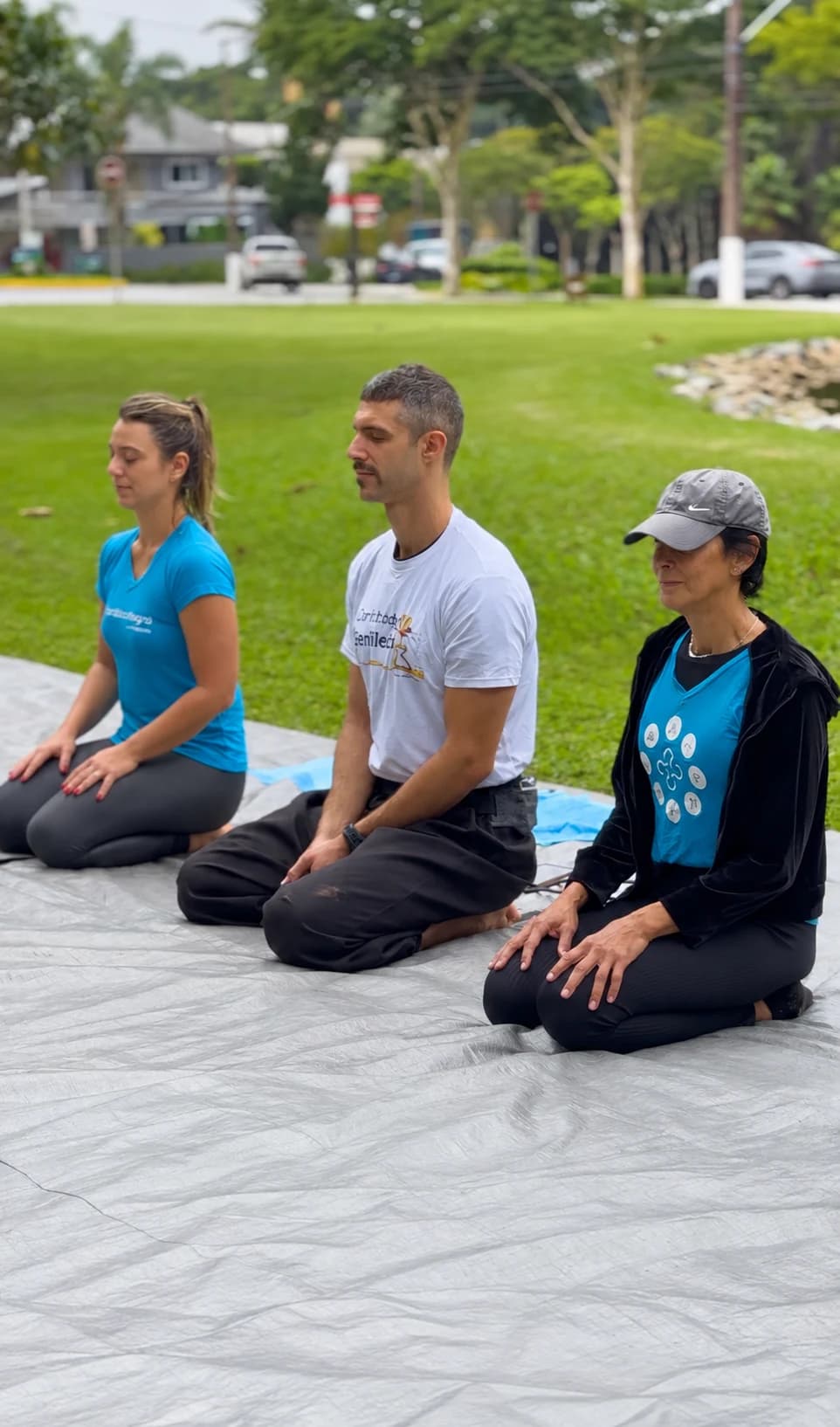 Participantes sentados de olhos fechados em uma prática de meditação ao ar livre